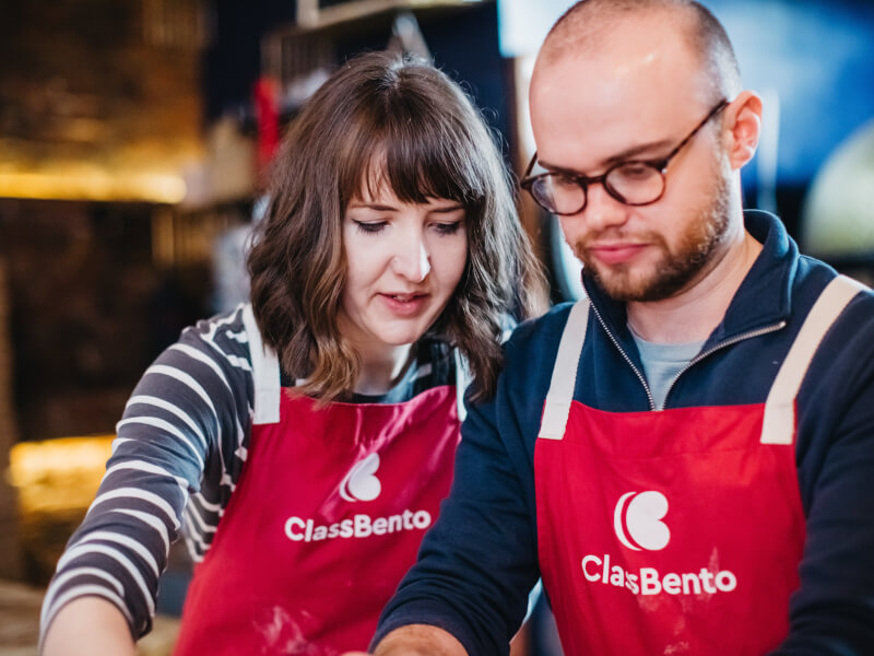 A couple wearing aprons at a cooking class.
